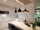 
                                    对比白色L型厨房与中岛吧台，黑色设计感灯具点缀新时代美学。
