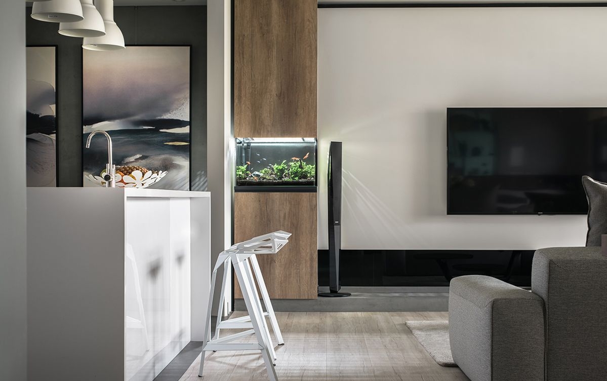 简洁大方的电视主墙无多余赘饰,仅在一隅以木质柜体嵌入造型鱼缸,成就
